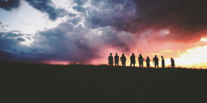 Silhouette of a group of people in a field at sunset.