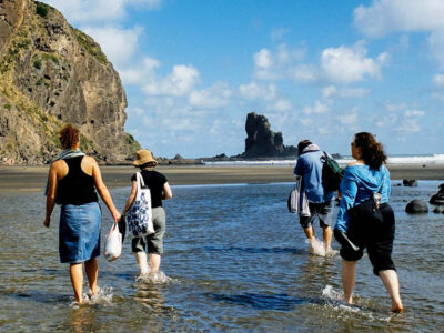 Group of travelers walking in the water on the beach.