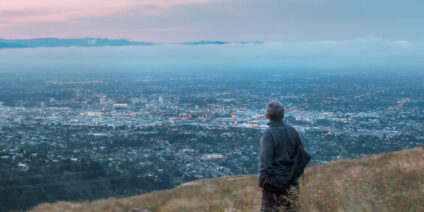 Solo traveler on a hill overlooking a city in New Zealand.